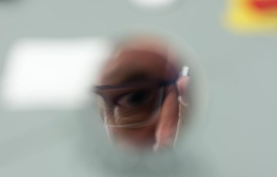 Na zdjęciu oko mężczyzny w okularach.Tło białe, rozmyte.