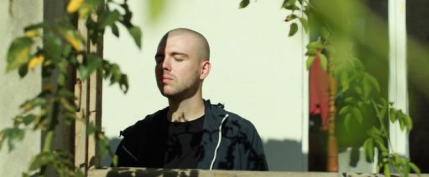 Na zdjęciu Daniel Kotowski. Ma zamknięte oczy, na pierwszym planie rośliny