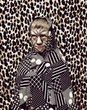 Dziecko z pomalowaną twarzą, nakryte materiałem, zakamuflowane