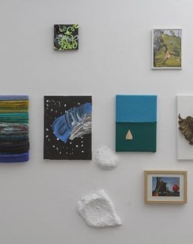 Na białej ścianie wiszą obrazy