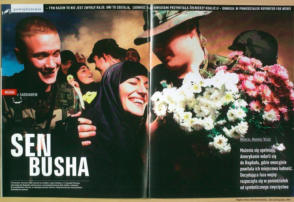 Fotografia przedstawia otwartą kolorową gazetę, tak rozłożoną, że wypełnia niemal cały kadr. Na otwartych stronach periodyku widnieje fotografia przedstawiająca irakijskie kobiety, witające z radością amerykańskich żołnierzy.