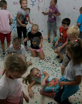 Dzieci podczas warsztatów malują farbami po ścianach.