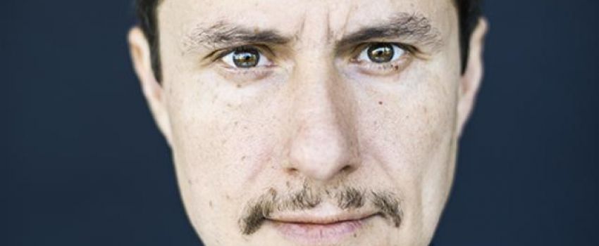 Na zdjęciu twarz mężczyzny na granatowym tle.