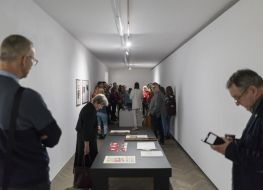 Na zdjęciu znajdują się ludzie w sali wystawowej oglądający elementy wystawy znajdującej się po środku pomieszczenia.