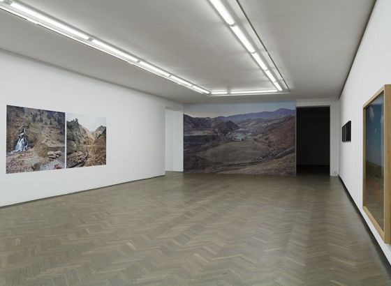Sala wystawowa. Wielkoformatowe fotografie przedstawiające krajobrazy umieszczone na ścianach pomieszczenia.