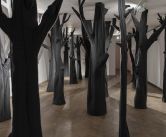 sala galerii wypełniona filcowymi ciemnoszarymi drzewami