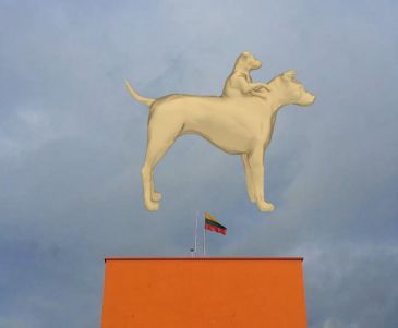 kadr z wideo na którym widzimy wygenerowaną komputerowo sylwetkę psa, któremu z grzbietu wyrasta popiersie mniejszego psa, w tle widać zachmurzone niebo i pomarańczowy budynek z masztem na którym powiewa flaga litewska
