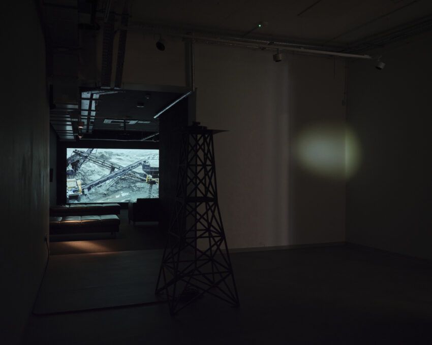 sala wystawiennicza po lewej stronie ekran z projekcją filmu po prawej punktowe świetło w ciemnej